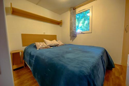 a bedroom with a large blue bed with a window at Manoir le Mingreaud Bungalows in Sainte-Gemme-la-Plaine