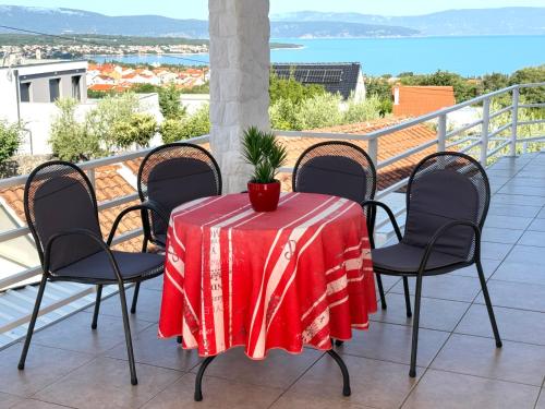 a table with a red table cloth on a balcony at Apartments Kremenici in Malinska