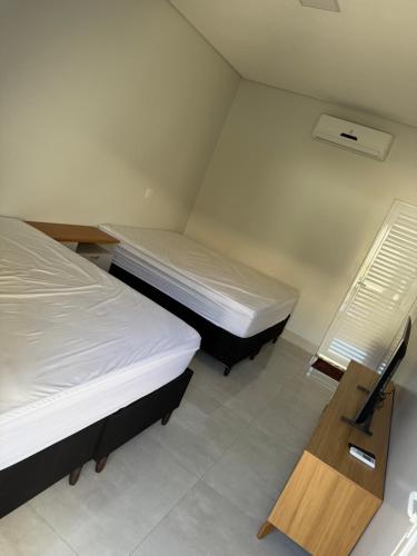 two beds in a small room with a wooden table at Residência Araguaia in Aruanã