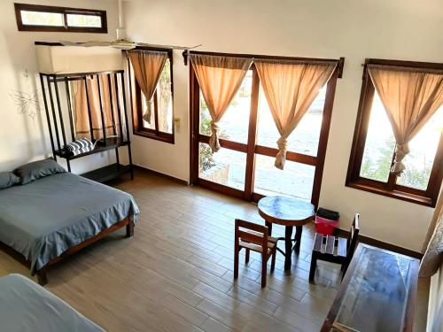 a bedroom with a bed and a table and windows at Casa Tania in Mazunte