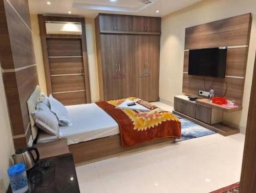 a bedroom with a large bed and a flat screen tv at Mavenoak Dreams B&B in Kolkata