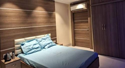 a bedroom with a blue bed with a wooden wall at Mavenoak Dreams B&B in Kolkata