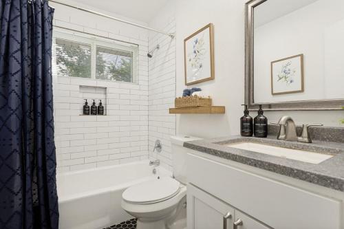 a white bathroom with a toilet and a sink at Italian Cottage 2B 1B Duplex KING Pet Friendly in Richardson