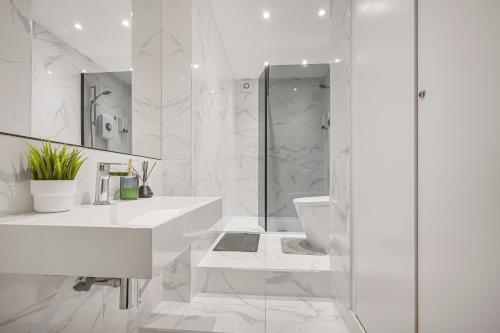 a white bathroom with a shower and a sink at Cosy Rooms in London