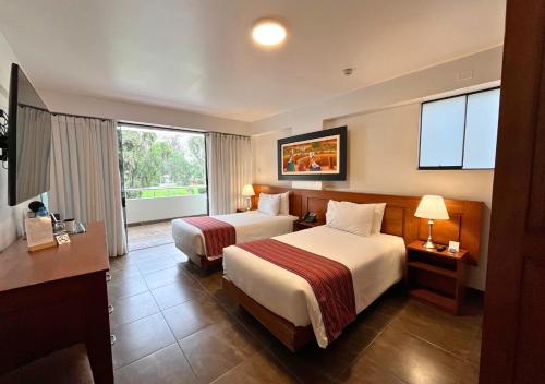 a hotel room with two beds and a desk at Kankay Hotel y Centro de Convenciones in Cieneguilla