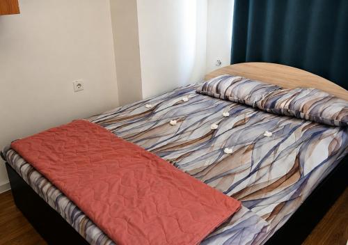 an unmade bed with a red comforter on it at Apartmani Anja in Ohrid