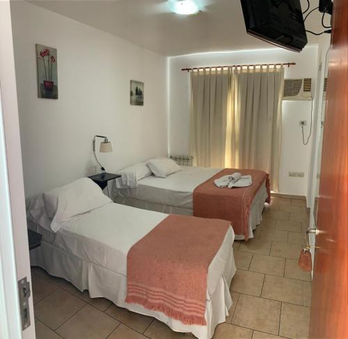 a hotel room with two beds and a television at Hostería Boulevard in Villa María
