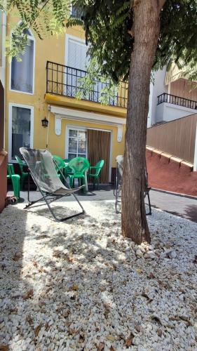 a chair and a tree next to a building at Villaparadisi in Benicàssim