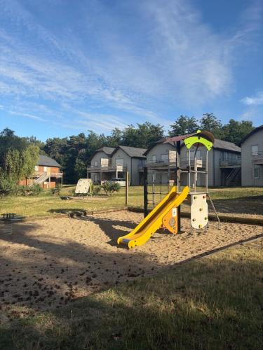 a playground with a yellow slide in a field at Chalet gris 4 in Chaveignes