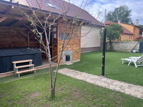 a small tree in front of a house with a bench at apartmany agnieszka in Smižany