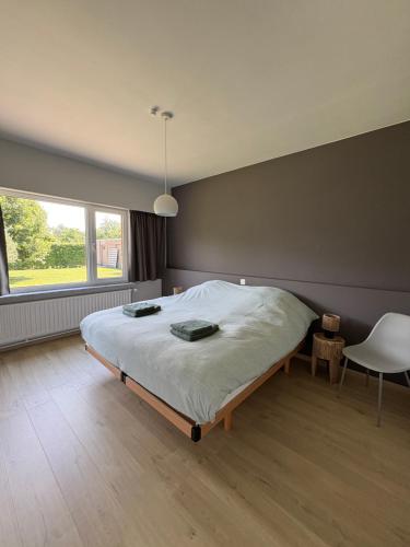 a bedroom with a bed and a chair and a window at De 50 Steenbrugge in Oostkamp
