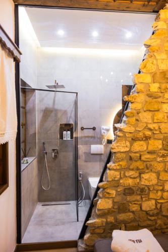 a bathroom with a walk in shower next to a stone wall at Vila Blin in Berat