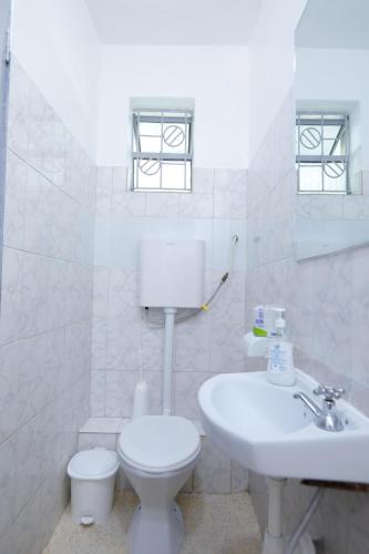 a white bathroom with a toilet and a sink at Self Contained Studio in Nakuru