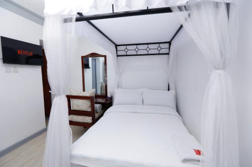 two beds in a room with white curtains at Self Contained Studio in Nakuru