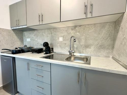 a kitchen with white cabinets and a sink at Mimoza Apartments in Limenaria