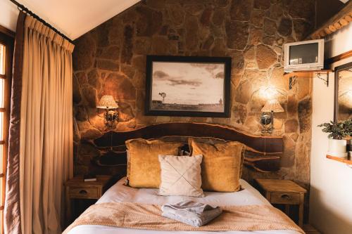 a bedroom with a stone wall with a bed at Garingboom Guest Farm in Groot-Suurfontein