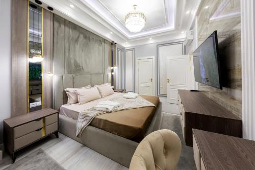a bedroom with a bed and a table and a tv at Gardence Residence Suite in Tashkent