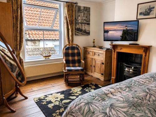 a bedroom with a bed and a television and a chair at Endeavour Cottage Whitby Quiet Old Yard Fishermans Cottage in Whitby