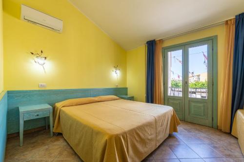 a yellow bedroom with a bed and a window at Hotel Del Corso in Pula