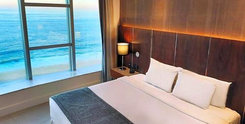 a bedroom with a bed and a window with the ocean at Hotel Nacional in Rio de Janeiro