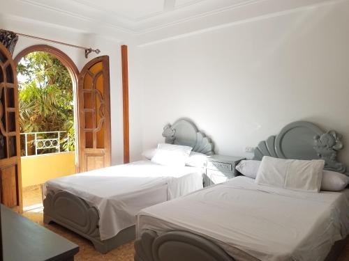 a bedroom with two beds and an open door at Nagar Villa Apartments in Luxor