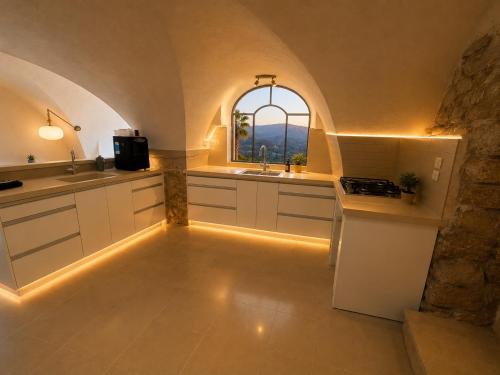 a kitchen with white cabinets and a sink and a window at וילת הארי בעתיקה in Safed