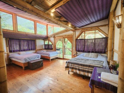 a bedroom with two beds in a room with windows at Bambu Guest House in Tzununá