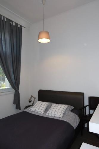 a bedroom with a black bed and a window at Apartament Bankowy in Olecko