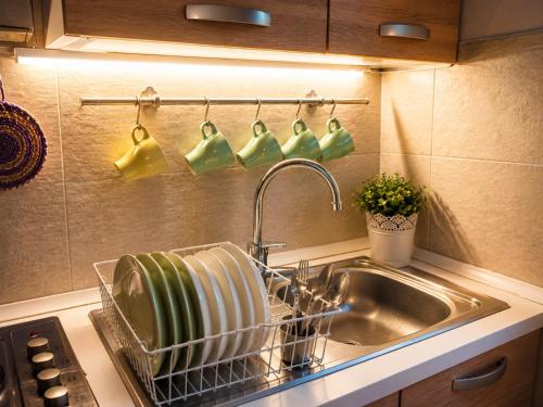 a kitchen sink with a dish drying rack and cups at B&B La Borasca - Apartments in Casalpusterlengo