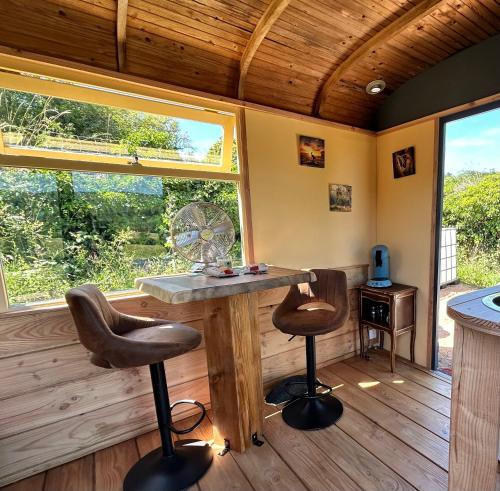 a room with a table and two stools in front of a window at Down under in France in Lormes
