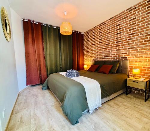 a bedroom with a bed and a brick wall at Le cocon d Albi in Albi