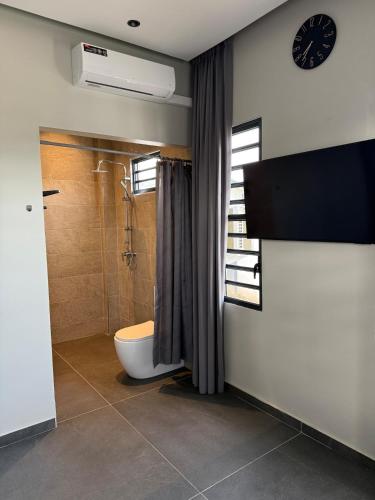 a bathroom with a toilet and a shower and a clock at Boa Vista villa in Paramaribo