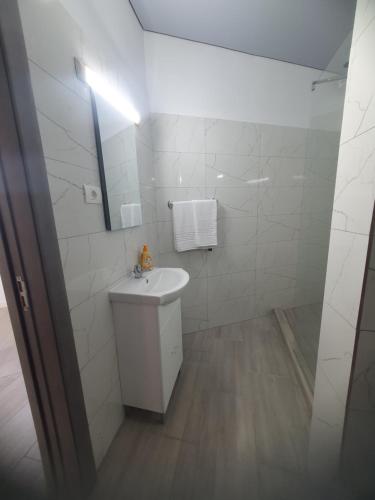 a white bathroom with a sink and a mirror at Constantin Rooms in Eforie Nord