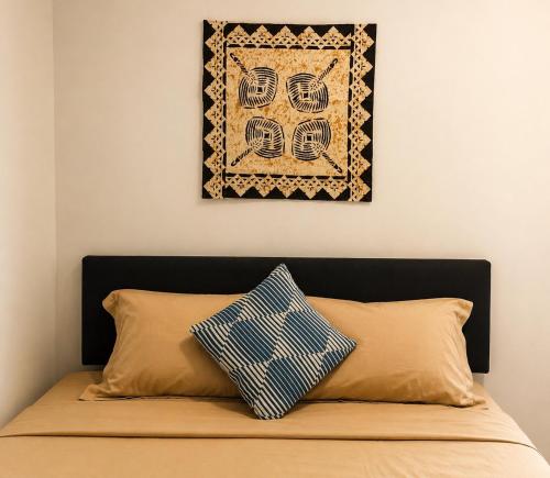 a picture hanging above a bed with a pillow at Nadi Airport Bed & Breakfast in Nadi