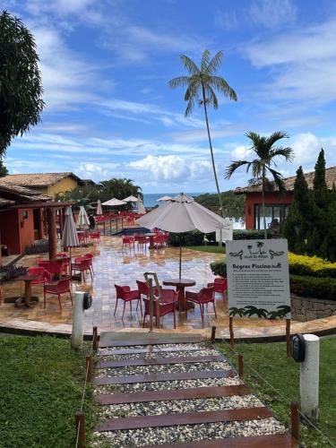 a pool with tables and chairs and an umbrella at Bangalô com Quarto, Sala, Varanda in Maceió