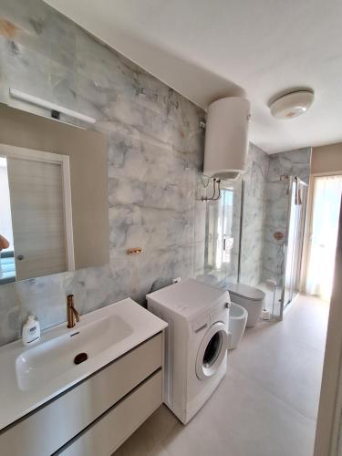 a bathroom with a sink and a washing machine at Onde e Relax D&D in Marina di Bibbona