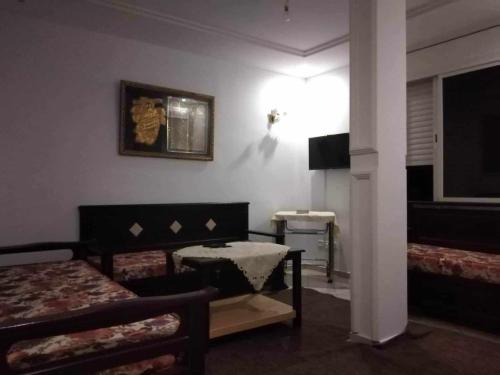 a room with two beds and a table and a television at Appartement Ezzdine sfaxi in Kelibia