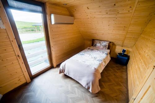 a bed in a wooden room with a large window at Domek na Bieszczadach Domek na Bani 2 in Łukowe