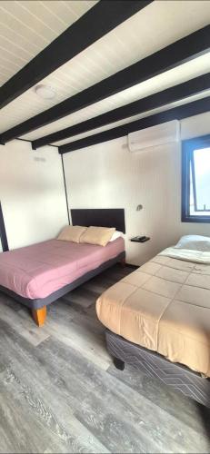 a room with two beds in a room with a window at Bambu hostal - Alojamiento a pasos del mall y centro in Los Ángeles