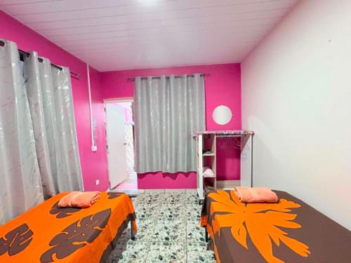 two beds in a room with pink and orange at CHEZ ALIZHIA in Nuku Hiva