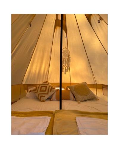 a bed in a tent with two pillows at Divlji Mir in Dobro Polje