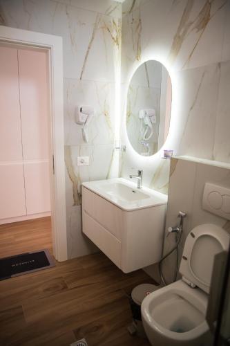 a bathroom with a toilet and a sink and a mirror at Hersol Skyline in Durrës