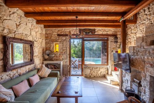 a living room with a couch and a tv at Forest stone Villa with pool in Kriopigi