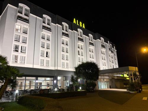 a large white building with aania on it at night at Hôtel Alba in Lourdes
