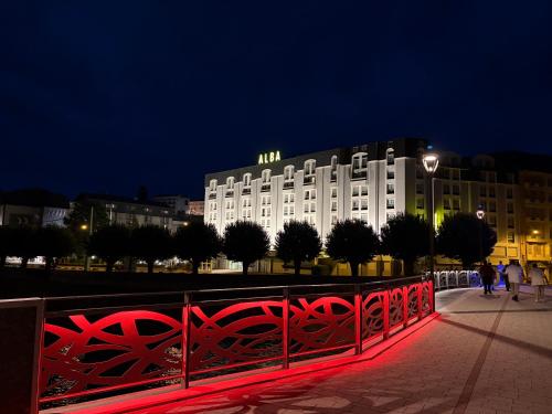 a white building with a red fence in front of it at Hôtel Alba in Lourdes