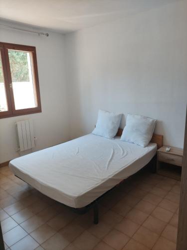 a bed with white sheets and pillows in a room at Maison 80 m2 - proche des plages in Montpellier