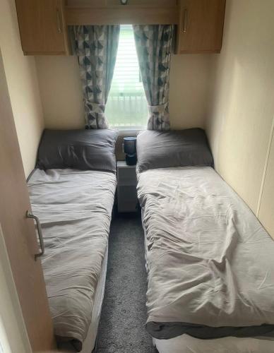 two beds in a small room with a window at Gemini in Heysham