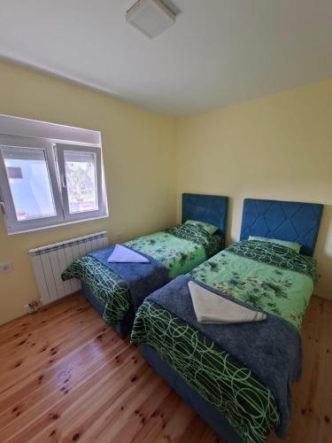 two beds in a room with wooden floors at Apartman Jana in Žabljak