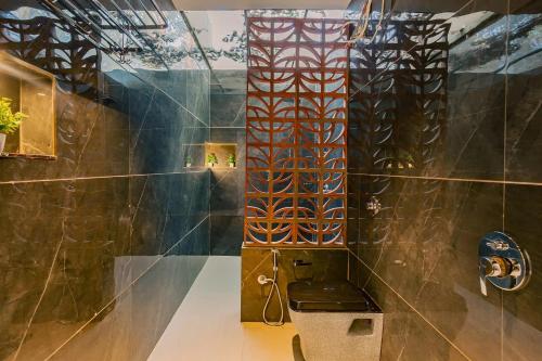 a bathroom with a toilet and a tile wall at The Marigold Villa in Pune