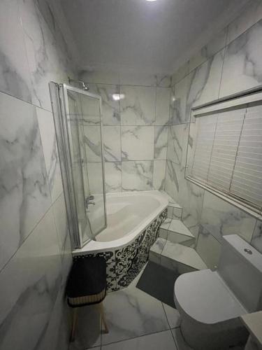 a white bathroom with a tub and a toilet at Mafofolozi Lodge in Hartbeespoort